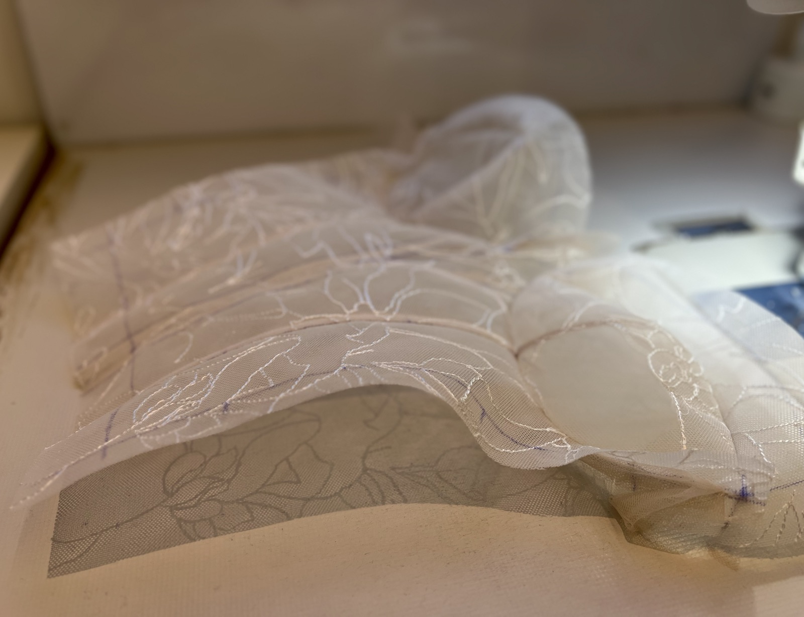 Close view of sheer embroidered lace being shaped by hand