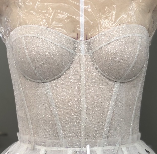 Silver-white structured corset with a subtle shimmer on a dress form