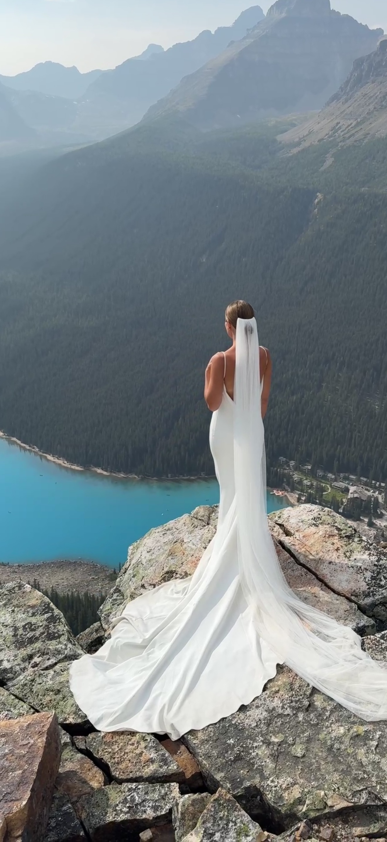 Bride in a custom white wedding gown overlooking a turquoise mountain lake