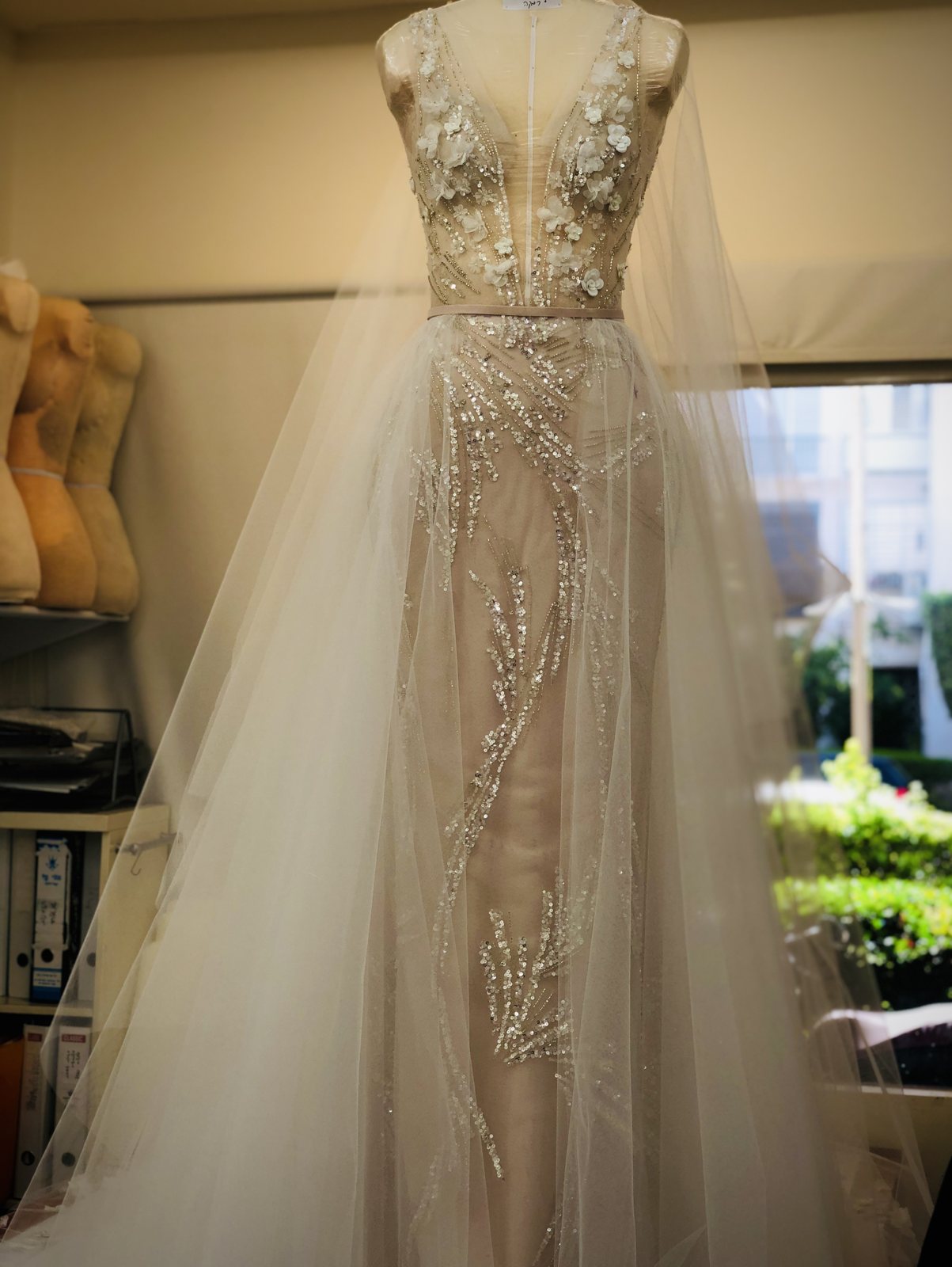 Embellished couture bridal gown with floral appliqué and a flowing overskirt