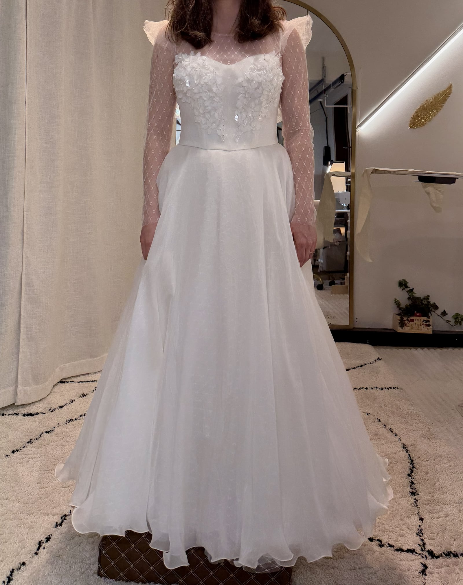 Custom bridal gown fitting with sheer sleeves and dimensional floral appliqué